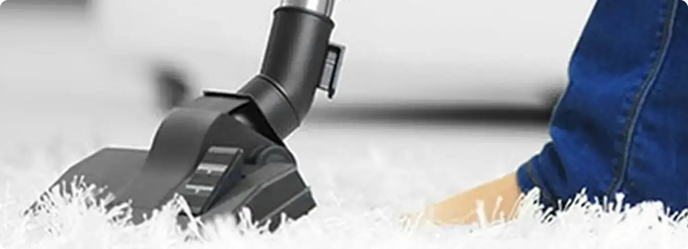 Close-up of a professional vacuuming a white carpet in Dania.
