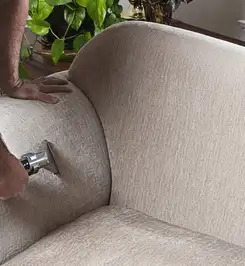 Professional upholstery cleaner deep-cleaning a fabric sofa with a handheld extraction tool and hose Fort Lauderdale, FL.